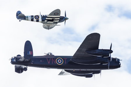 A World War Two Lancaster is escorted by a Spitfire fighter (from the same era) above the sky of Blackpool at a free seaside airshow in August 2017.のeditorial素材