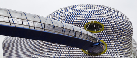 A man walks along the curved footbridge towards the iconic Selfridges Building in the heart of Birmingham city centre.  The building, which is part of the Bullring shopping centre was completed in 2003.  The facade comprises 15000 anodised aluminium discsのeditorial素材