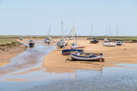 Boats by the quay at Wells next the Sea seen at low tide in June 2021 on the North Norfolk coast.