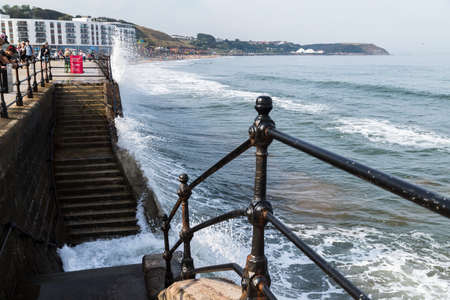 Waves crash into the steps and promenade at Scarborough as tourists watch on in September 2020.のeditorial素材