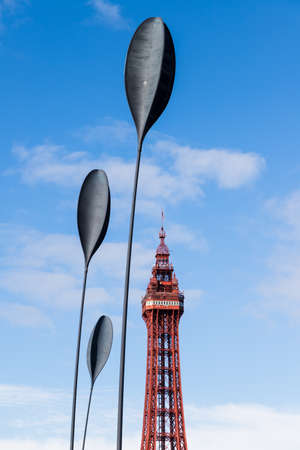 Dart sculptures seen in front of Blackpool Tower under a blue sky in September 2021.  The four tall sculptures bend and wave with the wind on the Blackpool seafront.のeditorial素材