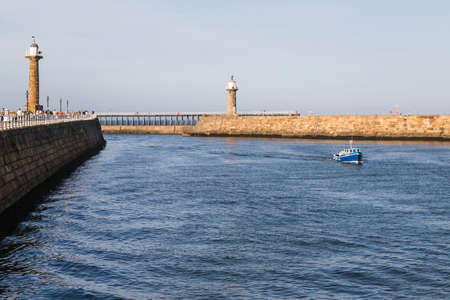 Fishing boat enters Whitby harbour between the two long piers.のeditorial素材