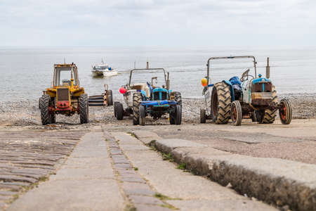 Looking down the slipway at three tractors at Cromer as a fishing boat awaits a recovery.  Seen in June 2021 on the North Norfolk coast.のeditorial素材