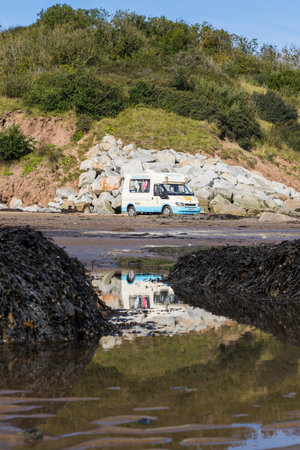 Ice cream van on the beach at Robin Hoods Bay reflecting in the rock pools at low tide in September 2020.のeditorial素材