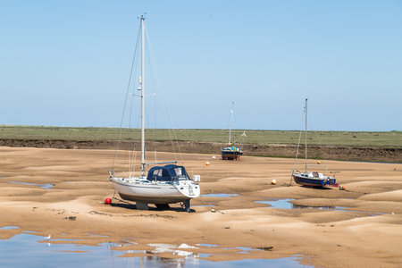 Trio of boats at Wells next the Sea beached by the low tide on the North Norfolk coast seen in the summer of 2021.のeditorial素材