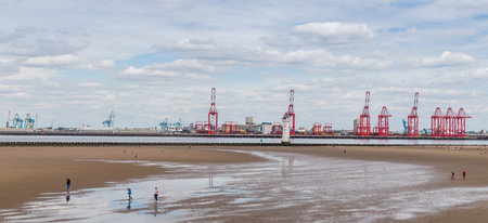 A multi image panorama of the red cranes on Liverpool docks towering above Wallasey beach.  Seen near Liverpool, England in July 2020.のeditorial素材