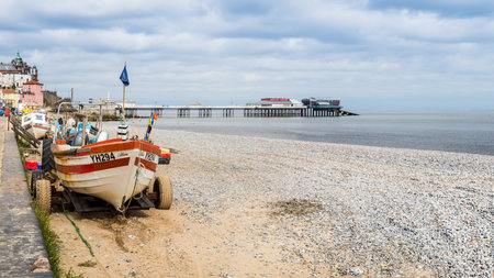 Tractors and fishing boats line the edge of Cromer beach in front of the pier.  Seen in June 2021 on the North Norfolk coast.のeditorial素材