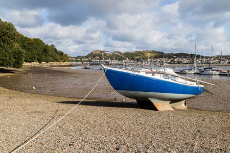 A small boat beached at low tide next to Conwy in North Wales seen in October 2021.