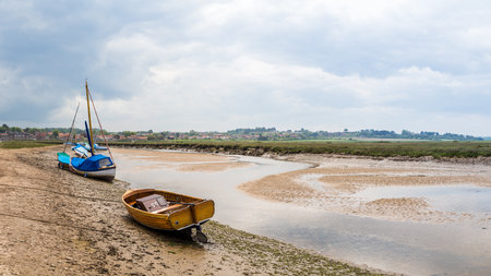 Multi image panorama of boats beached by the low tide at Blakeney in June 2021 on the North Norfolk coast.のeditorial素材