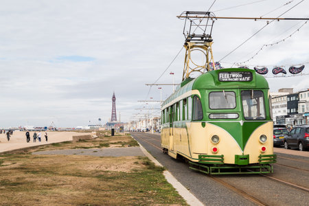 A traditional old tram seen in September 2021 travelling along the Golden Mile on the Blackpool seafront, heading towards Blackpool Tower which can be seen in the distance.のeditorial素材