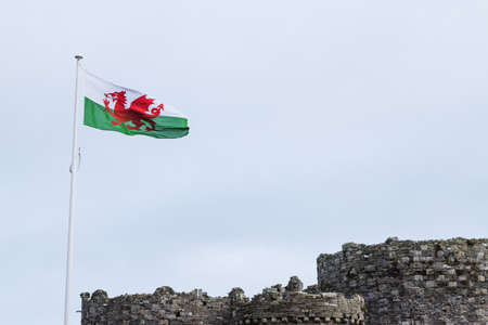 Looking up at the red dragon the Welsh flag seen above Beaumaris Castle in Wales during October 2021.のeditorial素材