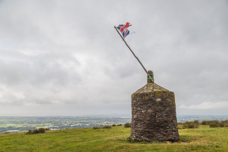 A battered Union Jack flag pictured on top of a Cairn in Garstang, Lancashire in September 2021.  It was originally built for the Golden Jubilee of Queen Victoria and was repaired for the Silver Jubilee of Queen Elizabeth II.のeditorial素材