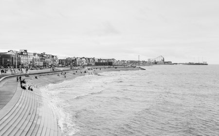 Tourists seen dotted along the Blackpool beach South promenade seen in black and white during September 2021.のeditorial素材