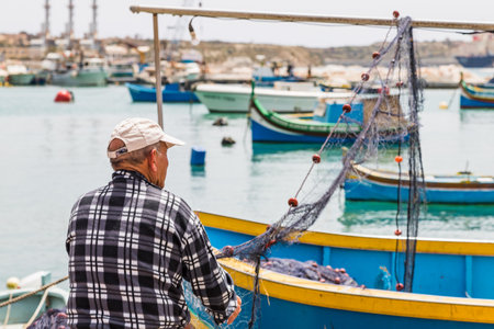 A fisherman seen inspecting his fishing nets Marsaxlokk, Malta in April 2022.のeditorial素材