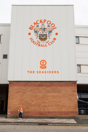 A senior woman dressed in an orange replica shirt and scarf walks to Bloomfield Road to watch Blackpool FC take on Barnsley FC in September 2021.のeditorial素材