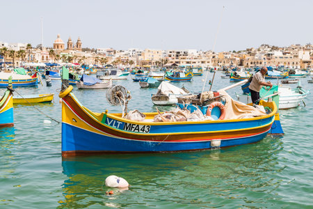 A fisherman takes his luzzu boat out of the harbour at Marsaxlokk, Malta in April 2022.のeditorial素材