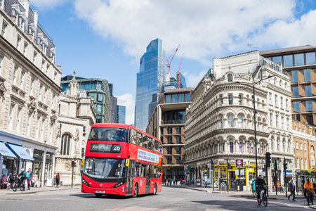 A red double decker bus travelling along Queen Victoria Street in London where it passes over Cannon Street in May 2022.のeditorial素材