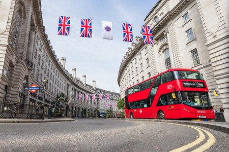 A traditional red double decker London bus at Piccadily Circus under rows of Union Jack flags in May 2022 as London prepares for the Queens Platinum Jubilee celebrations.のeditorial素材