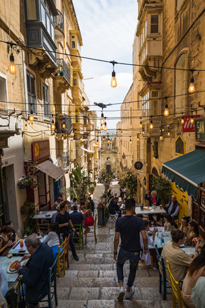 Lights hang over the steps full of tourists eating outside a popular restaurant in Valletta pictured in April 2022.のeditorial素材