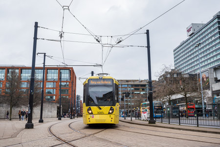 A closeup of a yellow Metrolink tram turning at Picadily Gardens in Manchester in February 2023.のeditorial素材