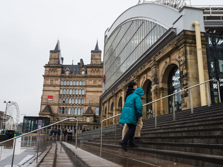 A man and woman walk up the wet steps under a rainy sky towards Liverpool Lime Street train station in December 2022.のeditorial素材