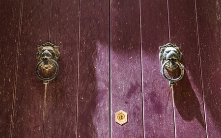 A pair of weathered door knockers pictured on a colourful door in Mdina, Malta in April 2022.の写真素材
