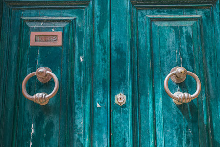 Door knockers on a brightly coloured weathered door in Mdina, Malta seen in April 2022.の写真素材