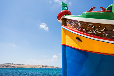 Luzzu boat next to the blue water at Bugibba, Malta in May 2022.の写真素材