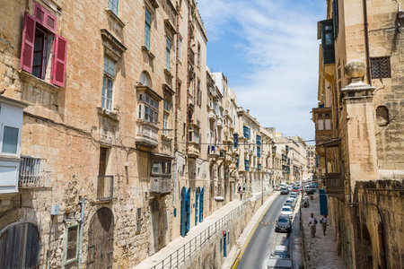 A typically colourful street in Valletta full of colourful balconies and shutters leading up into the sky, seen in Malta during April 2022.の写真素材