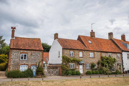 Traditional old cottages line the main road in the pretty Norfolk coastal village of Burnham Market seen in July 2022.の写真素材