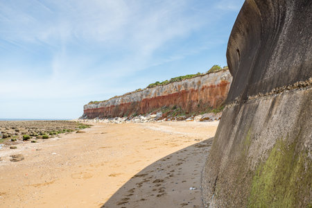 The curving seawall and promenade at Hunstanton meets the red and white coloured cliffs on the West Norfolk coast seen in July 2022.の写真素材