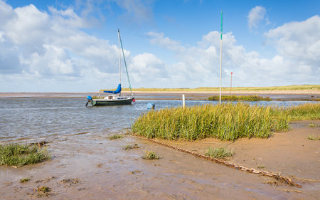 Yacht moored in the River Alt estuary seen in October 2022 from Hightown beach on the stunning Sefton coastline near Liverpool.の写真素材
