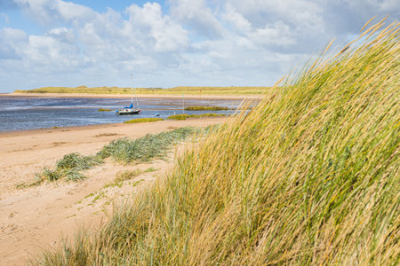 A lone yacht moored off the beach at Hightown near Liverpool seen in front of the dune grass in October 2022.の写真素材