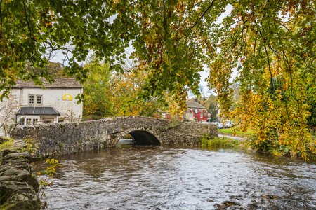 Malham Bridge seen spanning the Malham Beck in the heart of the Yorkshire Dales framed by the autumn coloured trees.の写真素材