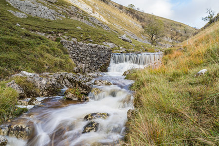 Fast flowing water captured as a long exposure flows over rocks along Bucken Beck in the Yorkshire Dales.の写真素材