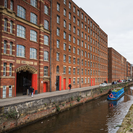 A blue narrow boat contrasts against the traditional red bricks of Royal Mill along Redhill Street in the Ancoats area of Manchester in February 2023.の写真素材