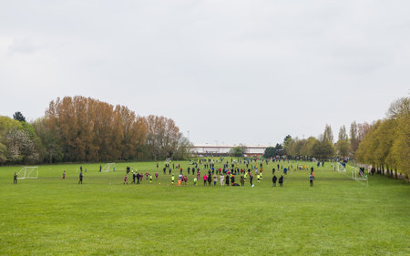 Numerous fields full of amateur children playing football in a park in Liverpool surrounded by watching families in April 2023.の写真素材