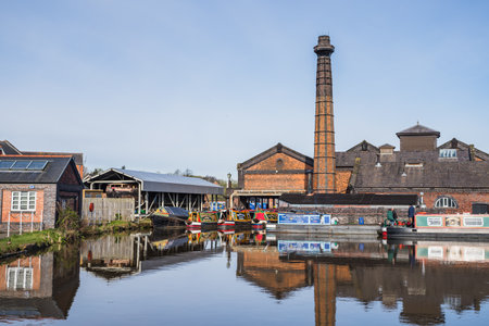 Narrow boats moored around the pump house at Ellesmere Port on the Ellesmere Canal reflect in the...