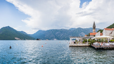 A multi image panorama of restaurants lining part of the Perast waterfront surrounded by steep mountains seen in May 2023.の写真素材