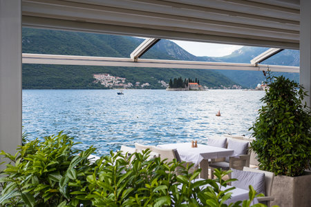 Tables set up on the waters edge at Perast with views along the Bay of Kotor and the two islets.の写真素材