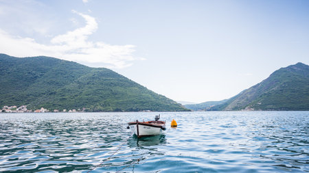 A lone boat in the Bay of Kotor moored to the shore of Perast, Montenegro seen in May 2023.の写真素材