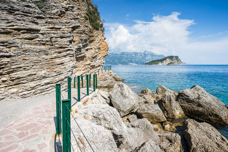 The railing line pathway winding under the cliffs from Mogren Beach to the Budva old town on the Montenegro coastline.の写真素材
