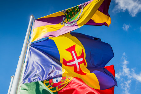Looking up at the bright flags of Funchal, Madeira & Portugal under a blue sky in Funchal.の写真素材