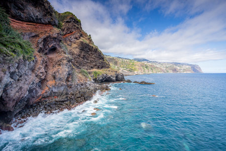 The rugged coastline at Ponta do Sol in Madeira as colourful cliffs and rocks meet the turquoise water of the Atlantic Ocean.の写真素材