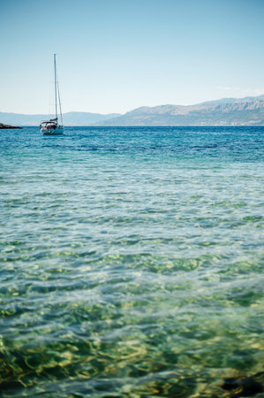 White tourist boat conducting tour on Adriatic sea with crystal clear water. High rocky mountains...