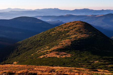 Beautiful morning sunrise over green peaks of mountains. Light fog around. Concept of calmness and...