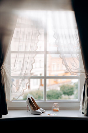 Wedding rings and shoes on the windowsill of the houseの写真素材