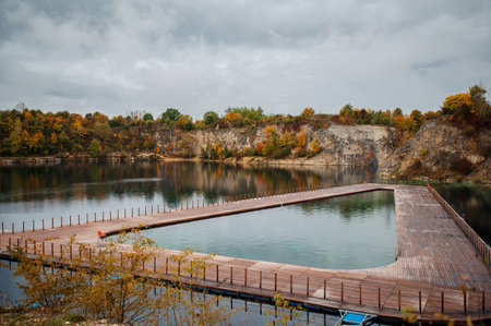 Wooden bridge over the lake in the autumn forest on a cloudy dayの写真素材