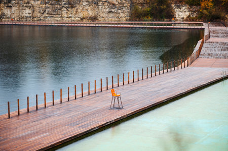 Beautiful view of the lake with a wooden pier and orange chairの写真素材