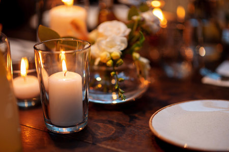 A cozy dining table setting with lit candles and floral decorations.